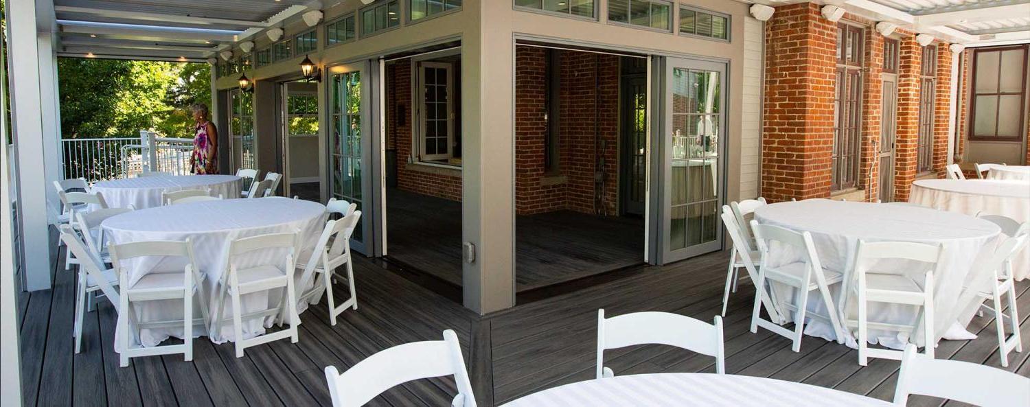 The covered outdoor patio of the Koenig Alumni Center, a historic house in Boulder, set up with event tables