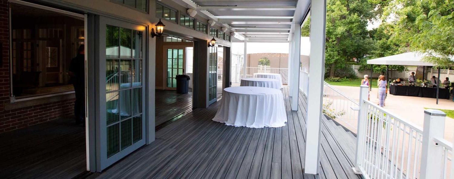 The covered outdoor patio of the Koenig Alumni Center in Boulder set up with event tables