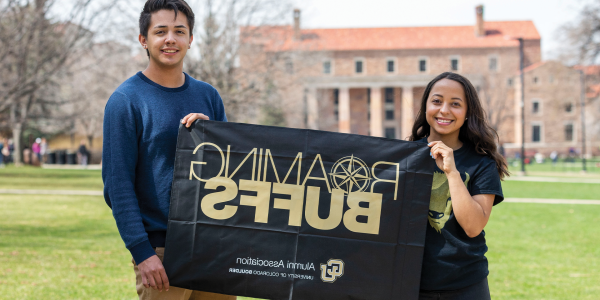 Alumni holding CU Boulder flag