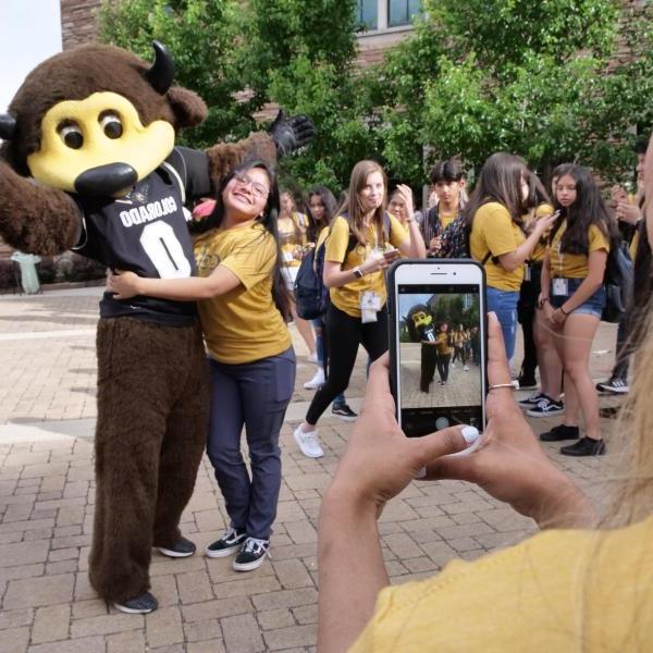 Student taking a picture of Chip the Buffalo with phone