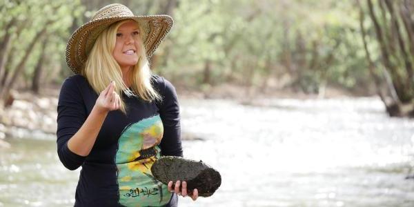 Student holding rock by stream