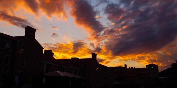 Silhouette of campus buildings with sunset in background